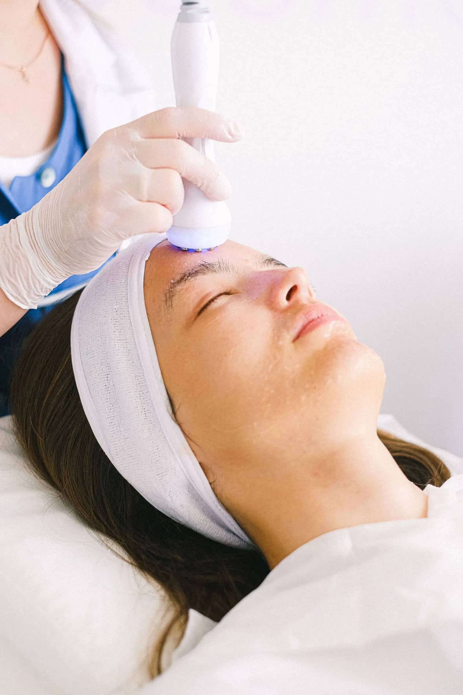 A patient receiving a facial treatment with a handheld device