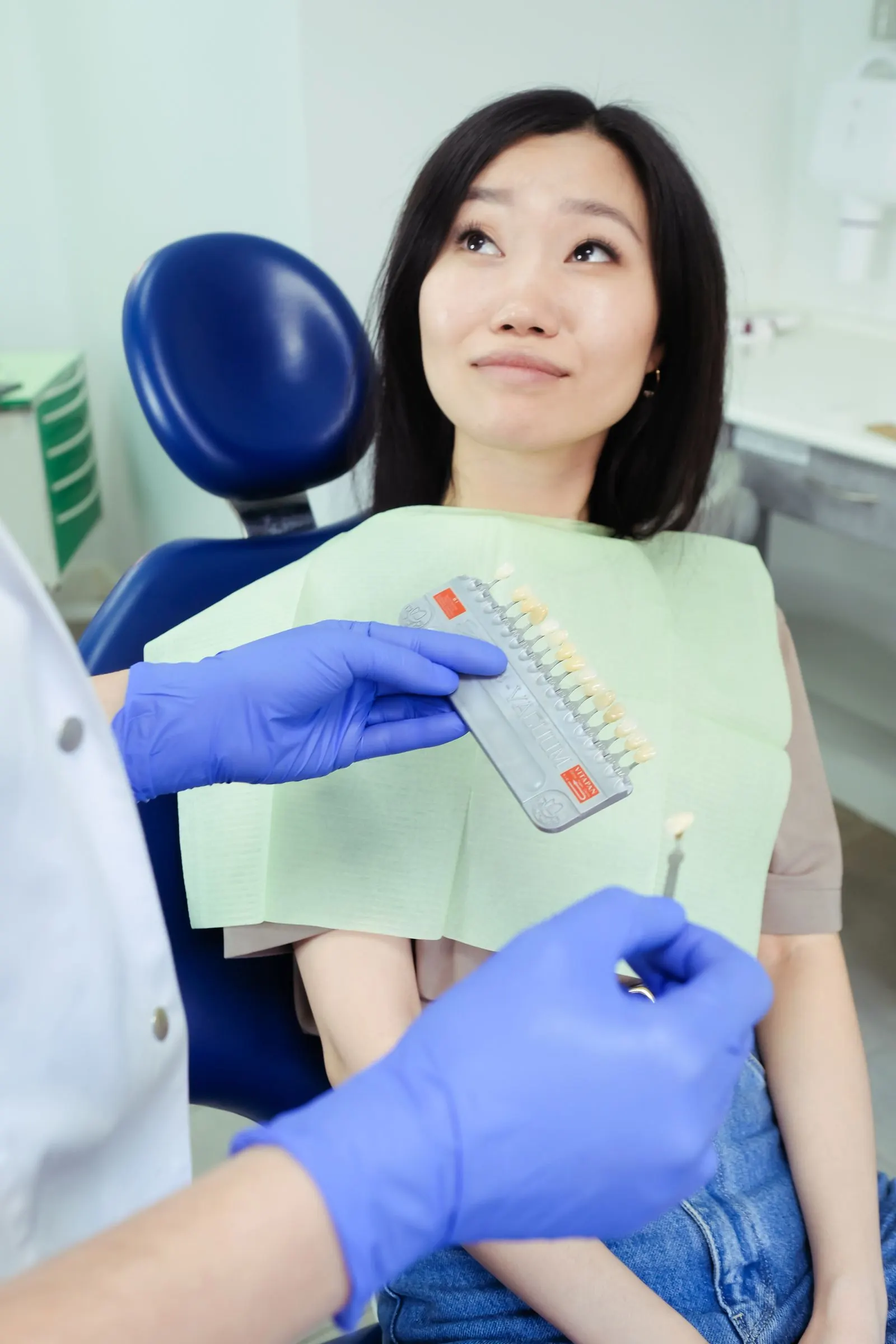 A dentist matching tooth shade for a patient in the dental chair